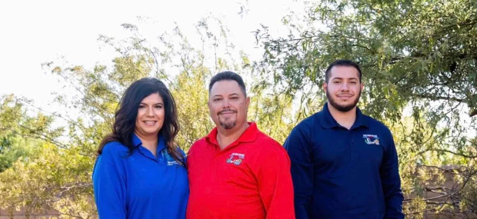 Three members of the Arenas family in Picture Rocks Cooling polos, standing among desert vegetation.