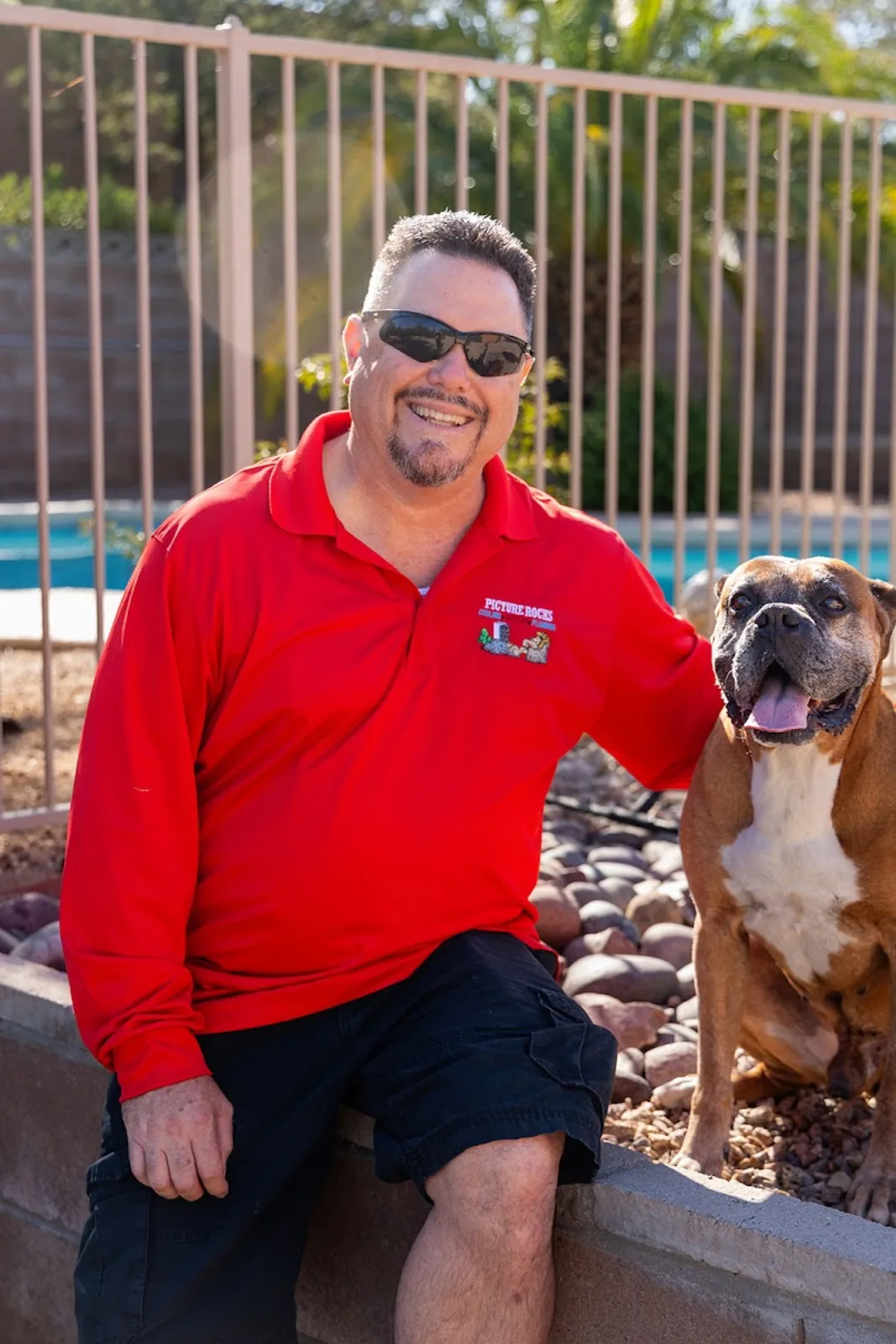 The owner in a red Picture Rocks Cooling polo with the family's boxer dog, representing the company's family-owned culture.